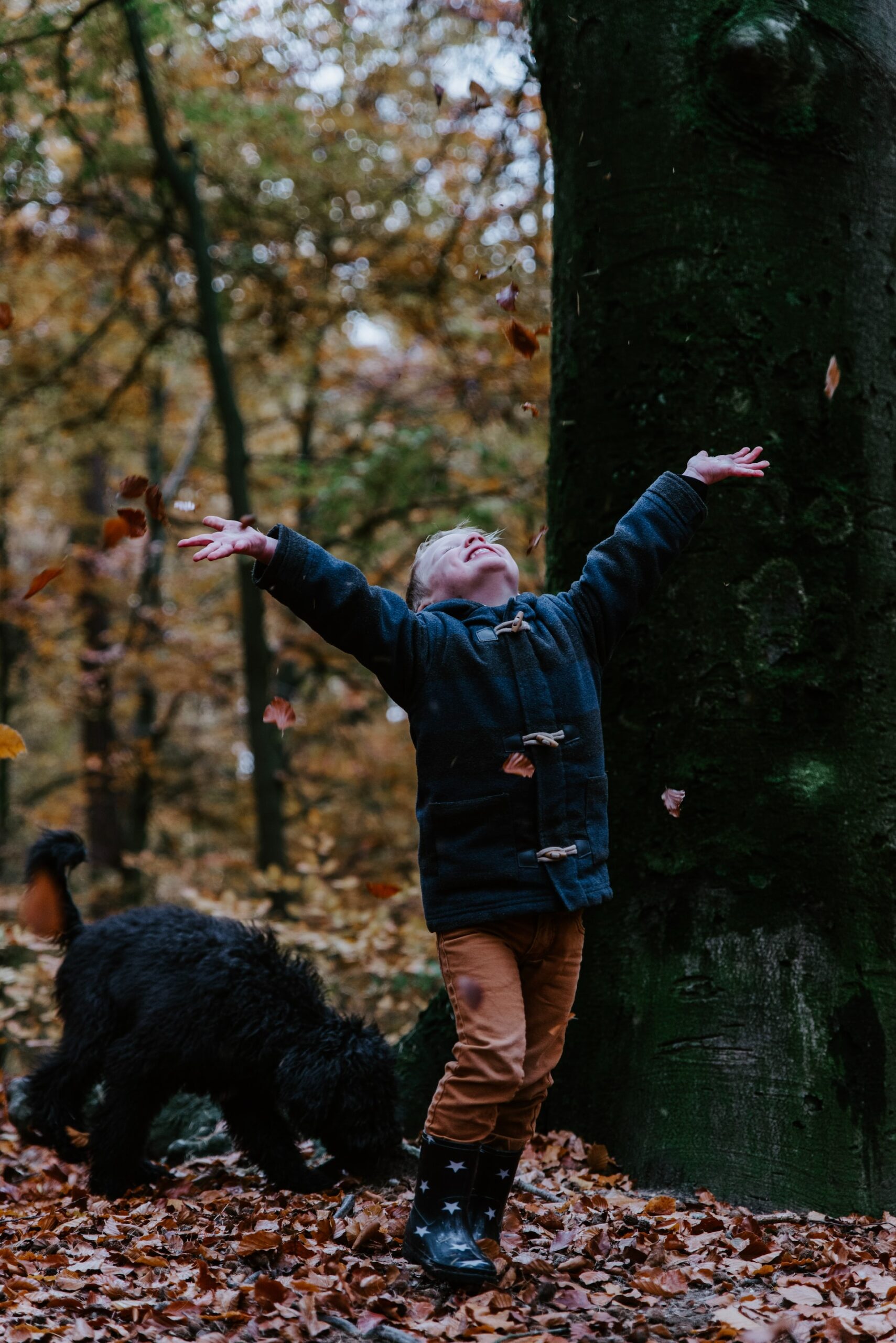 child throwing leaves in air