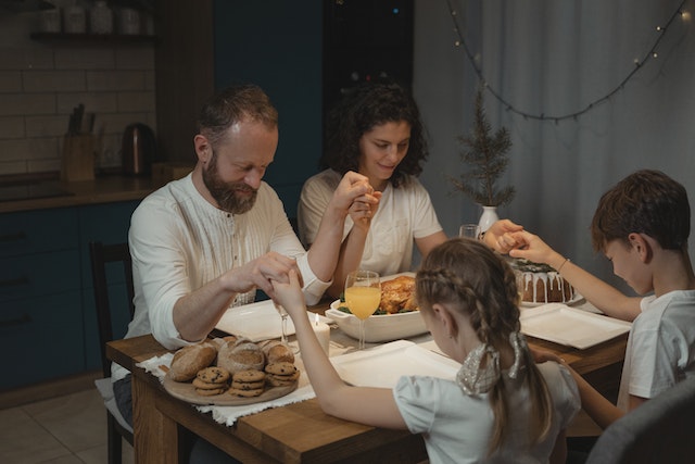 family praying together at dinner table