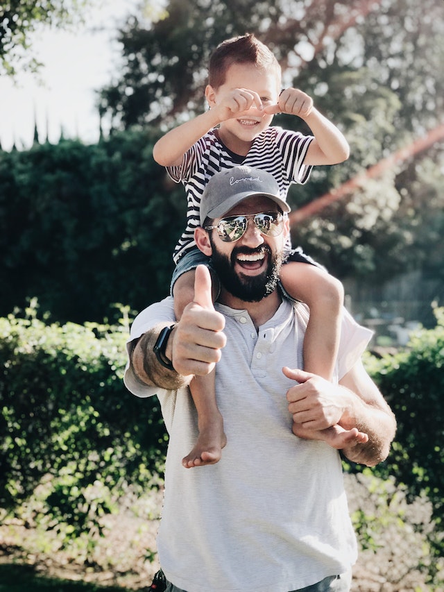 man with kid on shoulders
